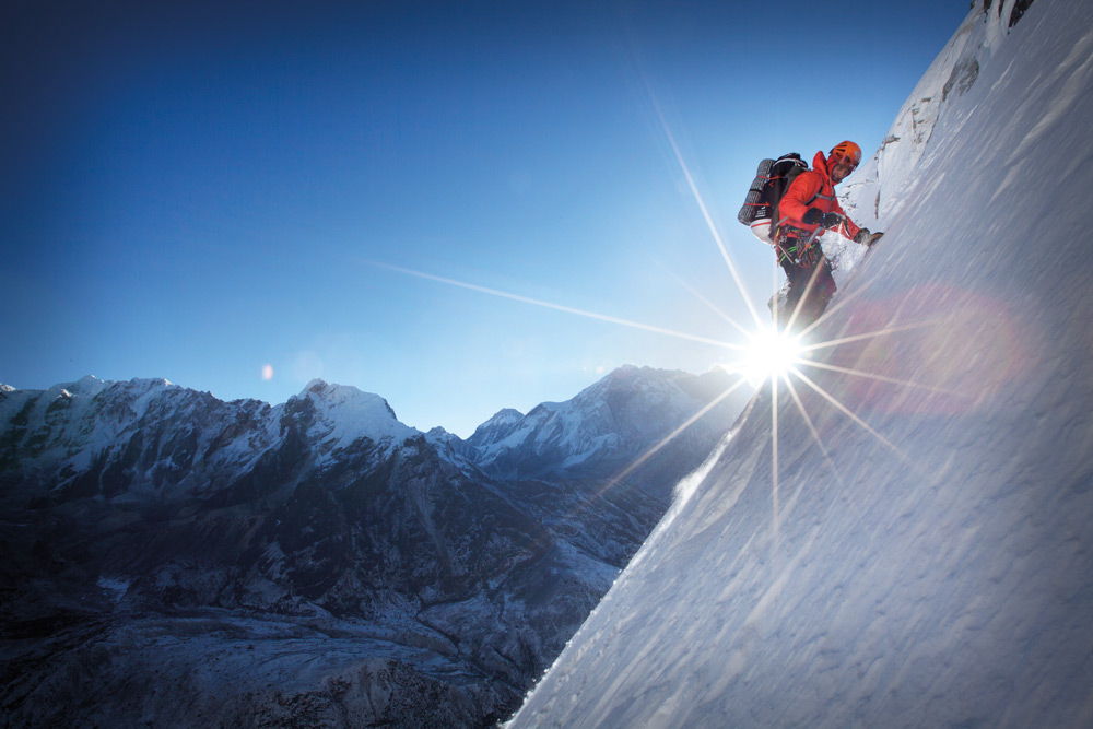Альпинист подымается на горную вершину