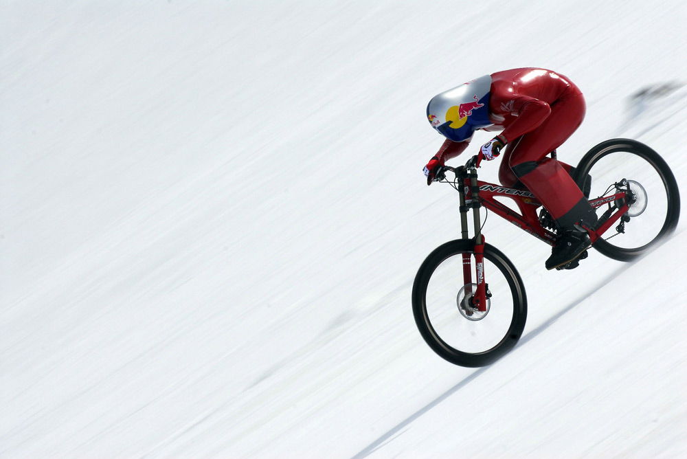 Спортсмен в аэродинамическом костюме спускается с горы на велосипеде
