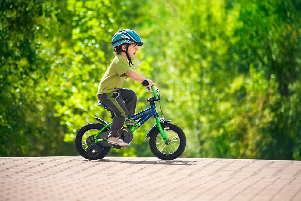 Мальчик катается на велосипеде по парку