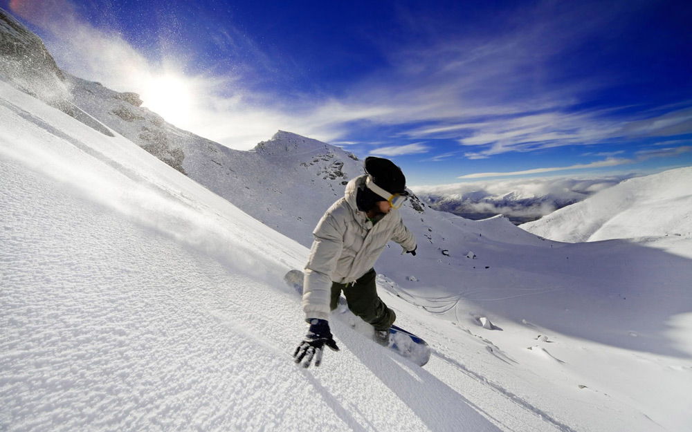 Человек спускается с горы на сноуборде