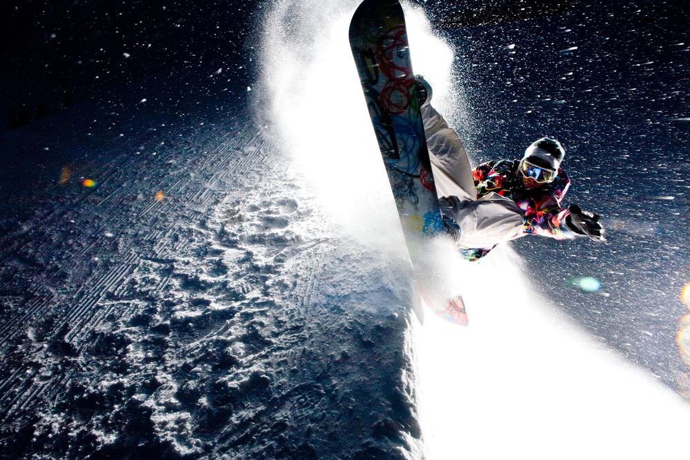 Спортсмен выполняет трюк на сноуборде
