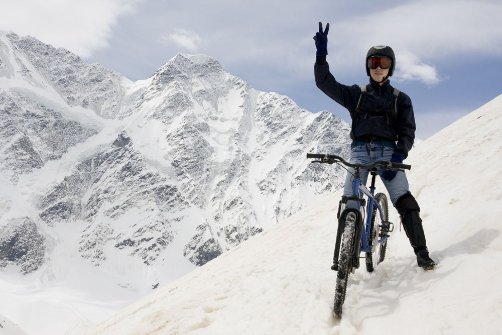 Человек на велосипеде в заснеженных горах