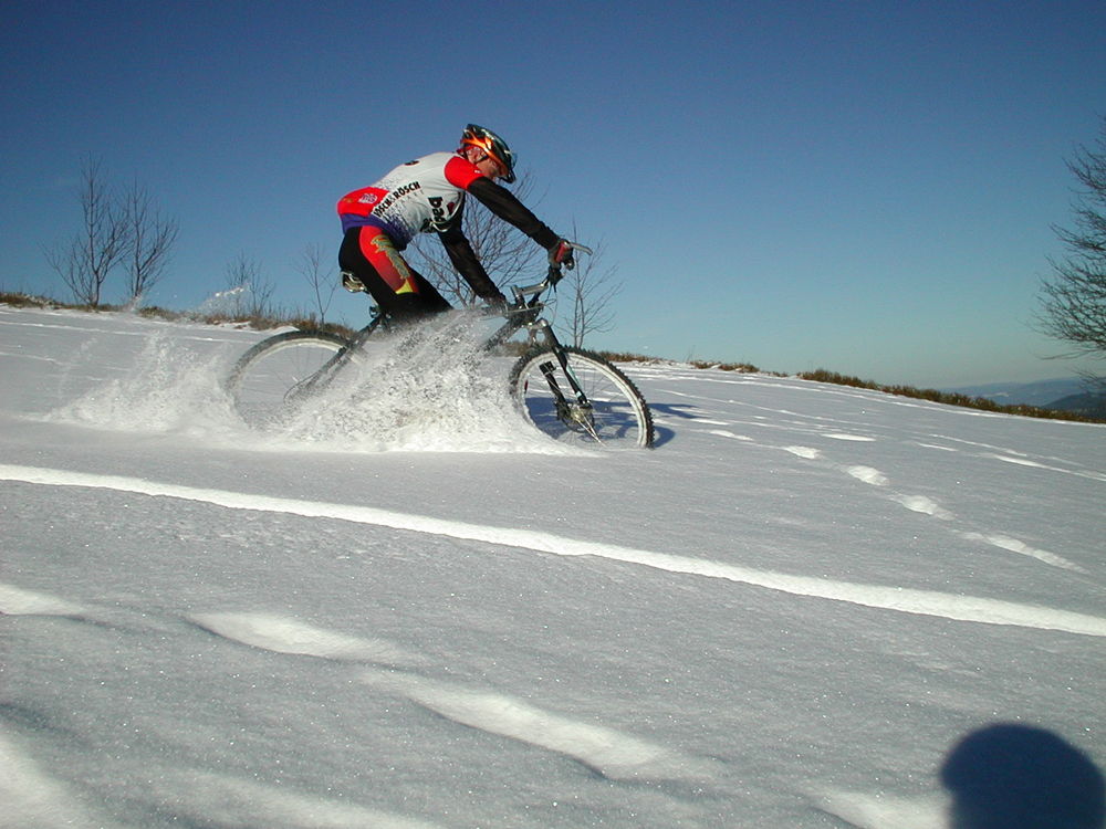 Спортсмен едет по снегу на велосипеде